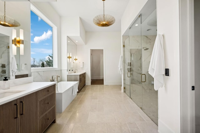 full bath featuring a sink, a soaking tub, a shower stall, and two vanities