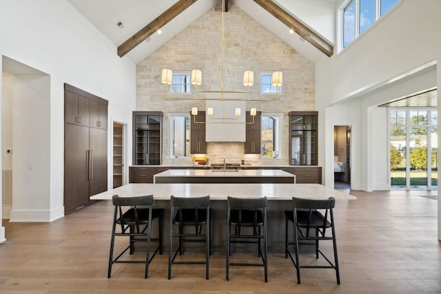 kitchen featuring a kitchen bar, a center island with sink, light countertops, and dark wood-type flooring