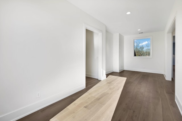 empty room with recessed lighting, dark wood finished floors, and baseboards