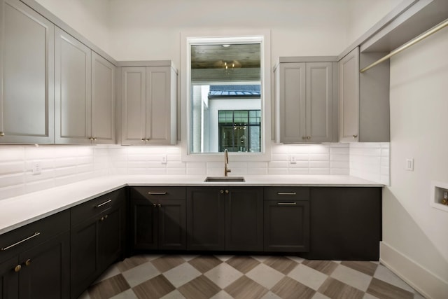 kitchen with light countertops, backsplash, a sink, and light floors