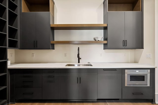 kitchen featuring modern cabinets, oven, light countertops, open shelves, and a sink