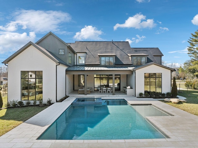 rear view of property with metal roof, fence, a pool with connected hot tub, a standing seam roof, and a patio area