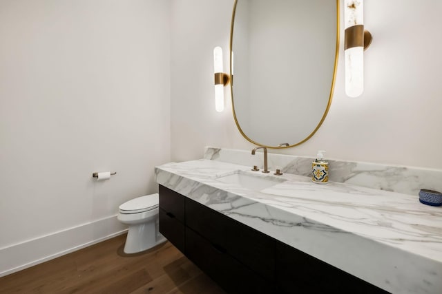 bathroom with toilet, wood finished floors, vanity, and baseboards