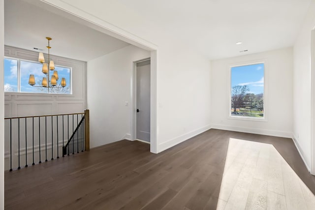 unfurnished room featuring baseboards, visible vents, a chandelier, and dark wood-style flooring