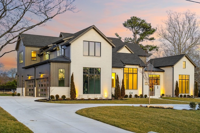 modern farmhouse featuring brick siding, roof with shingles, concrete driveway, a garage, and a front lawn