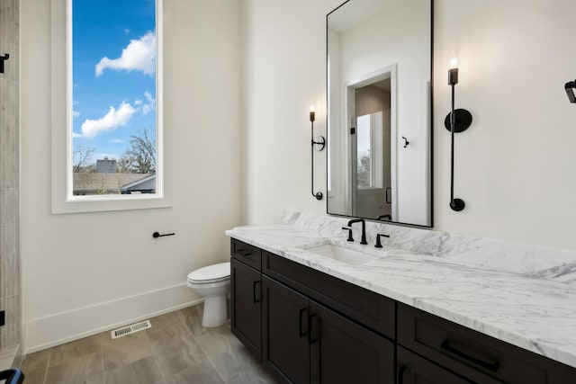 bathroom with toilet, baseboards, visible vents, and vanity