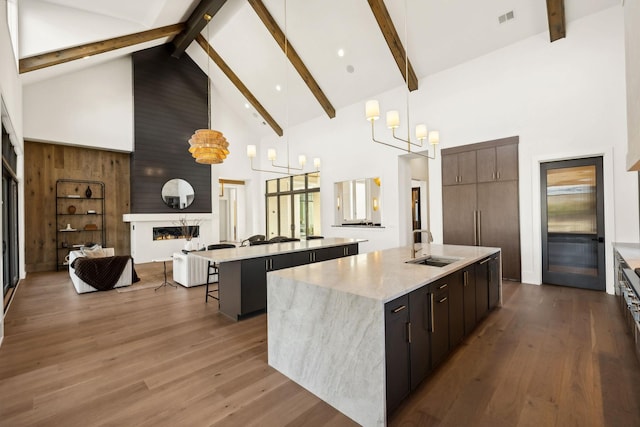 kitchen featuring a large fireplace, a sink, open floor plan, a large island, and dark wood-style floors