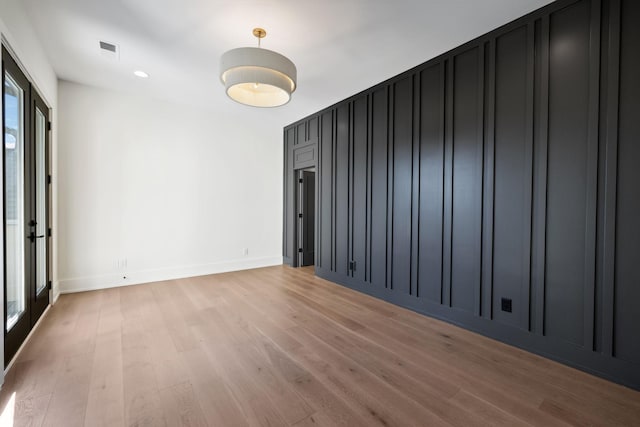 empty room with light wood-style flooring, visible vents, and baseboards