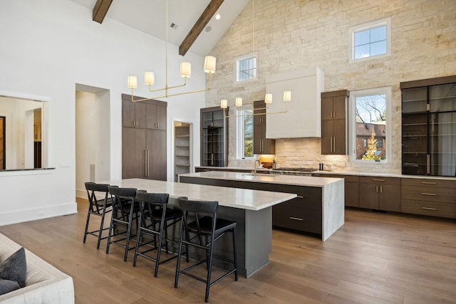 kitchen featuring a spacious island, dark wood-style flooring, beam ceiling, a kitchen bar, and backsplash