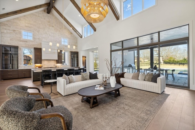 living area with light wood-type flooring, high vaulted ceiling, and beam ceiling