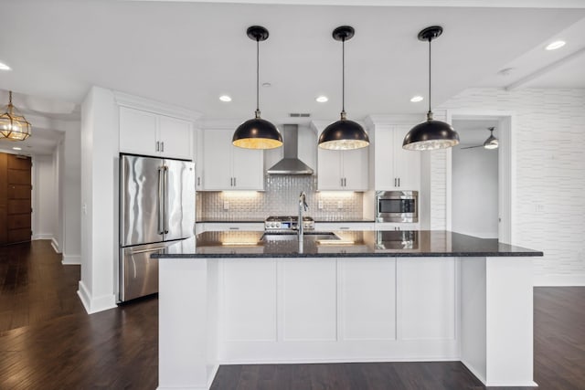 kitchen with wall chimney range hood, white cabinetry, appliances with stainless steel finishes, and pendant lighting