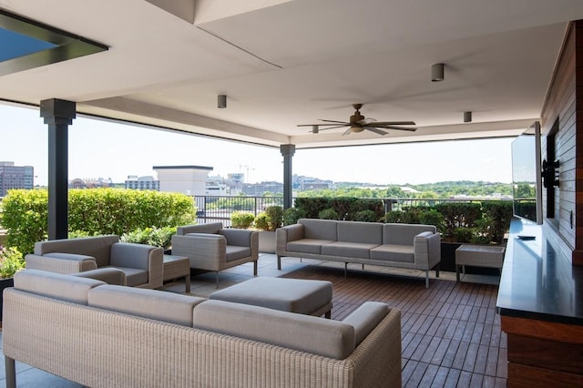 view of patio with outdoor lounge area, fence, a ceiling fan, and a city view