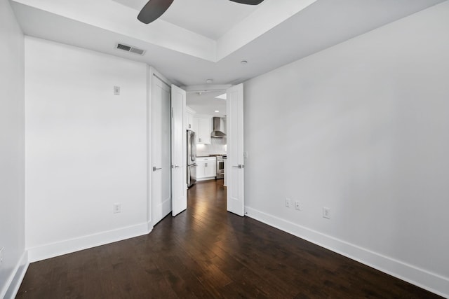 empty room with ceiling fan, dark wood-style flooring, visible vents, and baseboards