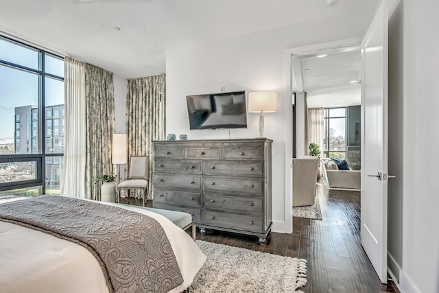 bedroom featuring baseboards, a city view, dark wood finished floors, and floor to ceiling windows