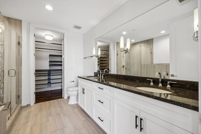 full bathroom with a walk in closet, double vanity, visible vents, a sink, and a shower stall