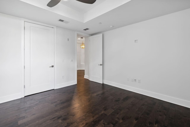 unfurnished bedroom with dark wood-style floors, ceiling fan, visible vents, and baseboards