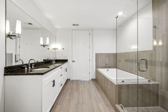 full bathroom with a sink, visible vents, a shower stall, a bath, and double vanity