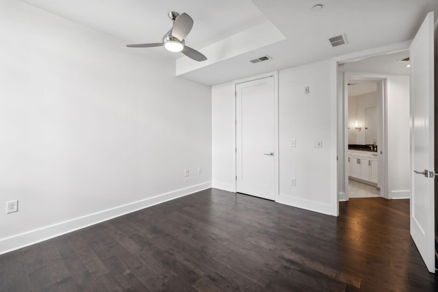 unfurnished bedroom featuring baseboards, visible vents, ceiling fan, and dark wood-type flooring