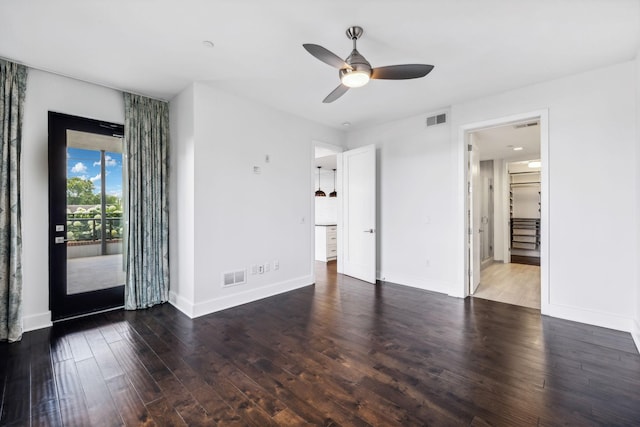 interior space with baseboards, access to outside, visible vents, and dark wood-type flooring