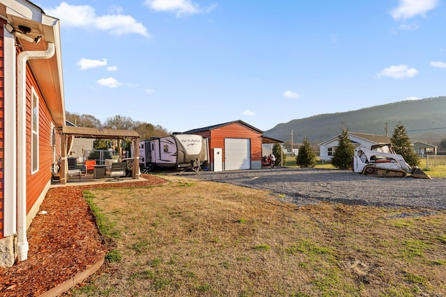 view of yard featuring a garage, a patio area, an outbuilding, and a mountain view