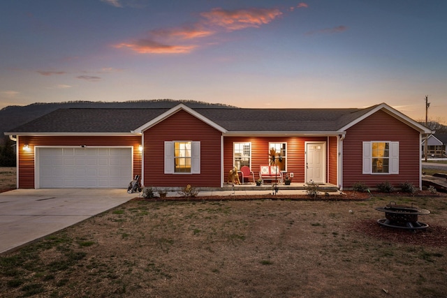 single story home with a shingled roof, covered porch, an outdoor fire pit, a garage, and driveway