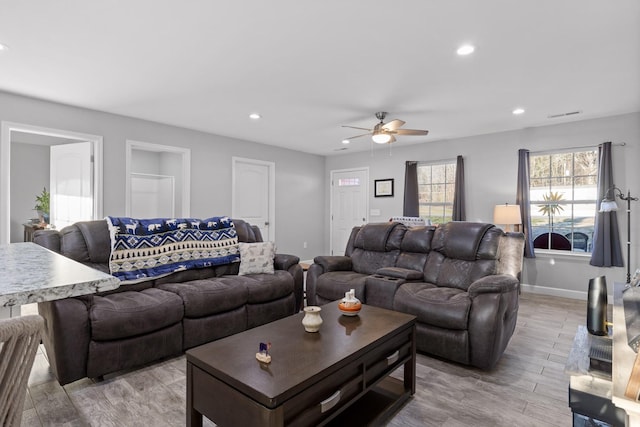 living room featuring baseboards, light wood finished floors, a ceiling fan, and recessed lighting