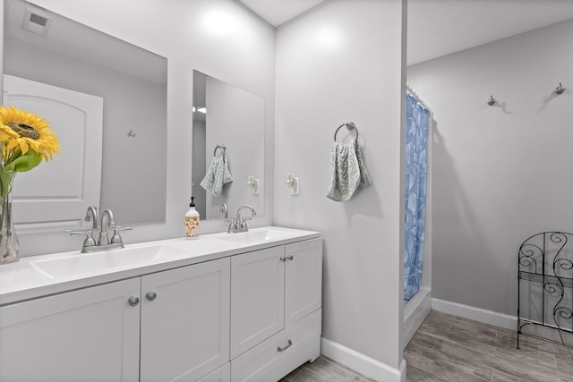 bathroom with double vanity, curtained shower, a sink, and visible vents