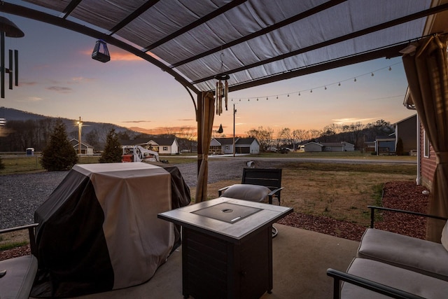 patio terrace at dusk featuring area for grilling, a residential view, and a pergola