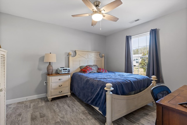 bedroom featuring a ceiling fan, visible vents, baseboards, and wood finished floors