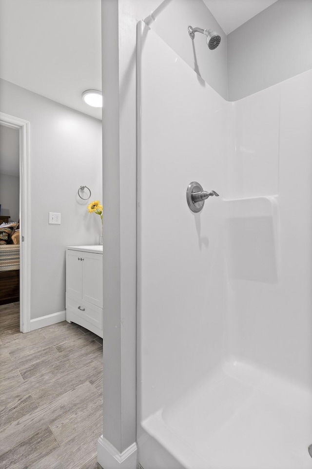 bathroom featuring wood finished floors, baseboards, and walk in shower