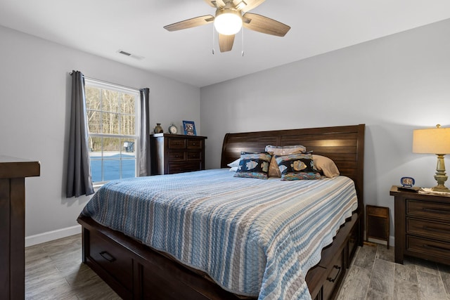 bedroom with light wood finished floors, ceiling fan, visible vents, and baseboards