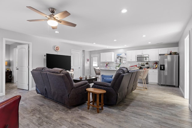 living area featuring light wood finished floors, baseboards, a ceiling fan, and recessed lighting