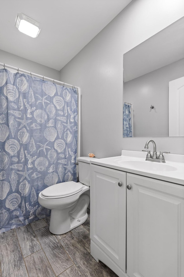 bathroom with toilet, wood finish floors, and vanity