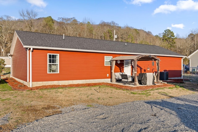 view of front of property with central AC unit, roof with shingles, and a patio area