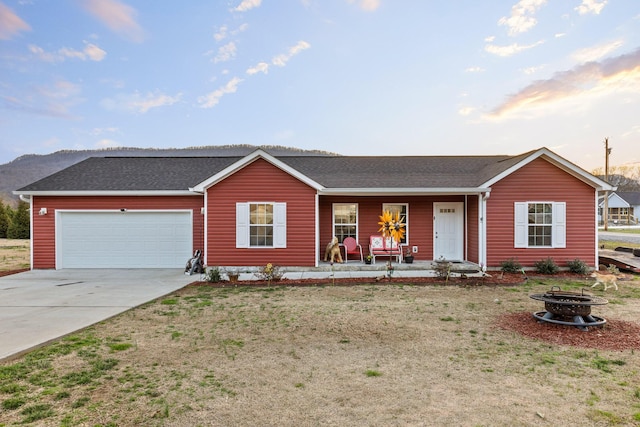 single story home featuring an attached garage, a fire pit, covered porch, concrete driveway, and roof with shingles