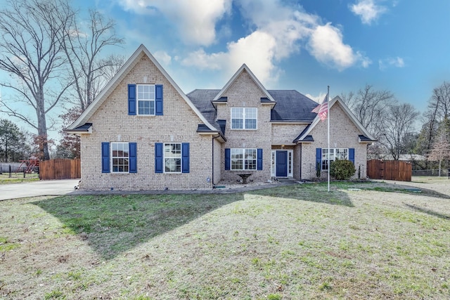 traditional-style house featuring fence, a front lawn, and brick siding