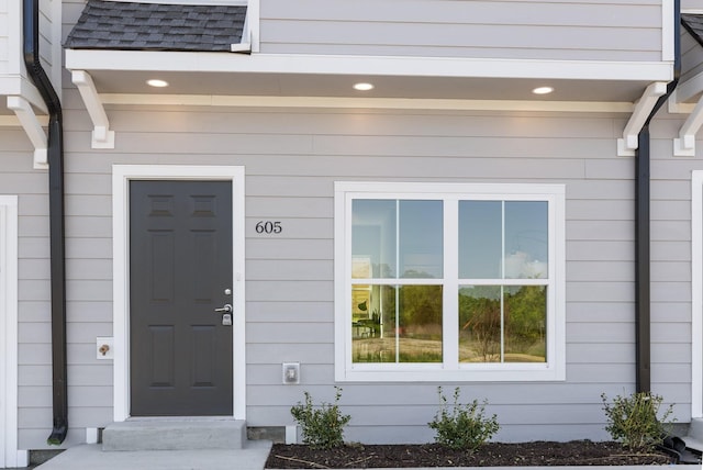 view of exterior entry with a shingled roof