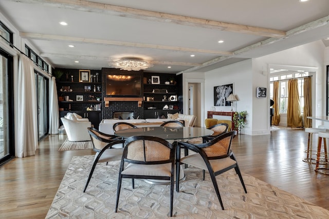 dining room featuring recessed lighting, a fireplace, baseboards, beam ceiling, and light wood finished floors