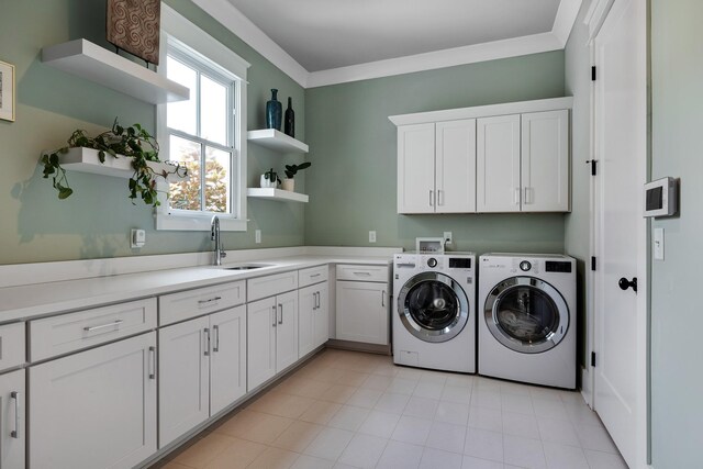 laundry area featuring cabinet space, crown molding, separate washer and dryer, and a sink