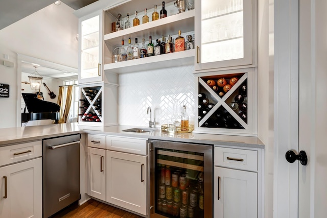 bar with wine cooler, a sink, stainless steel dishwasher, tasteful backsplash, and indoor wet bar