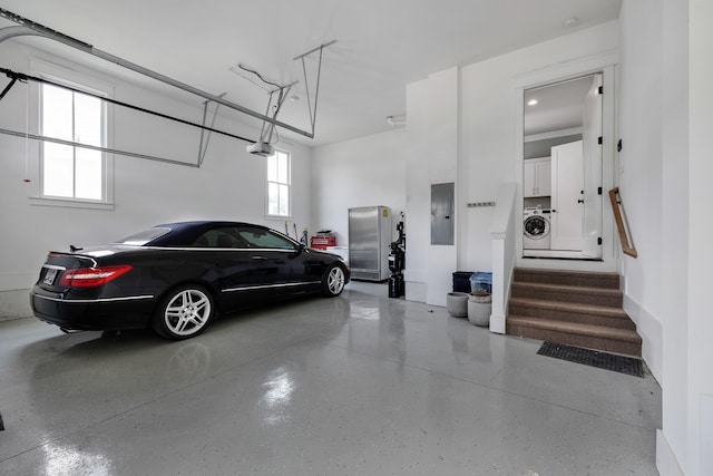 garage featuring washer / dryer, electric panel, and a garage door opener