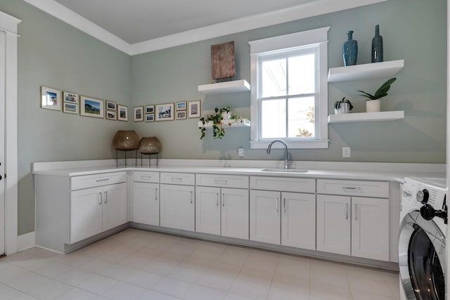 kitchen with open shelves, washer / clothes dryer, light countertops, white cabinets, and a sink