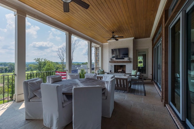 view of patio featuring a ceiling fan, outdoor dining space, and a fireplace