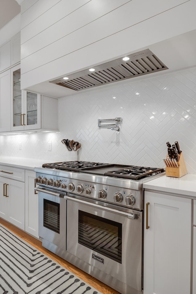 kitchen with white cabinets, decorative backsplash, range with two ovens, glass insert cabinets, and light countertops