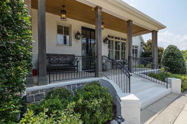 entrance to property with a porch and brick siding