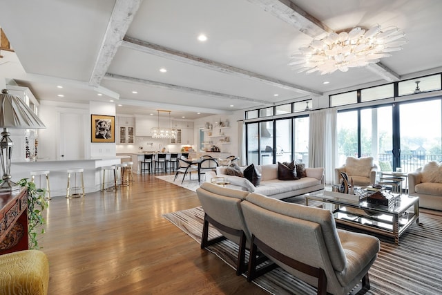 living area featuring a chandelier, beamed ceiling, dark wood finished floors, and a wealth of natural light