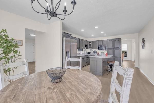 dining room with a chandelier, recessed lighting, light wood-style floors, and baseboards