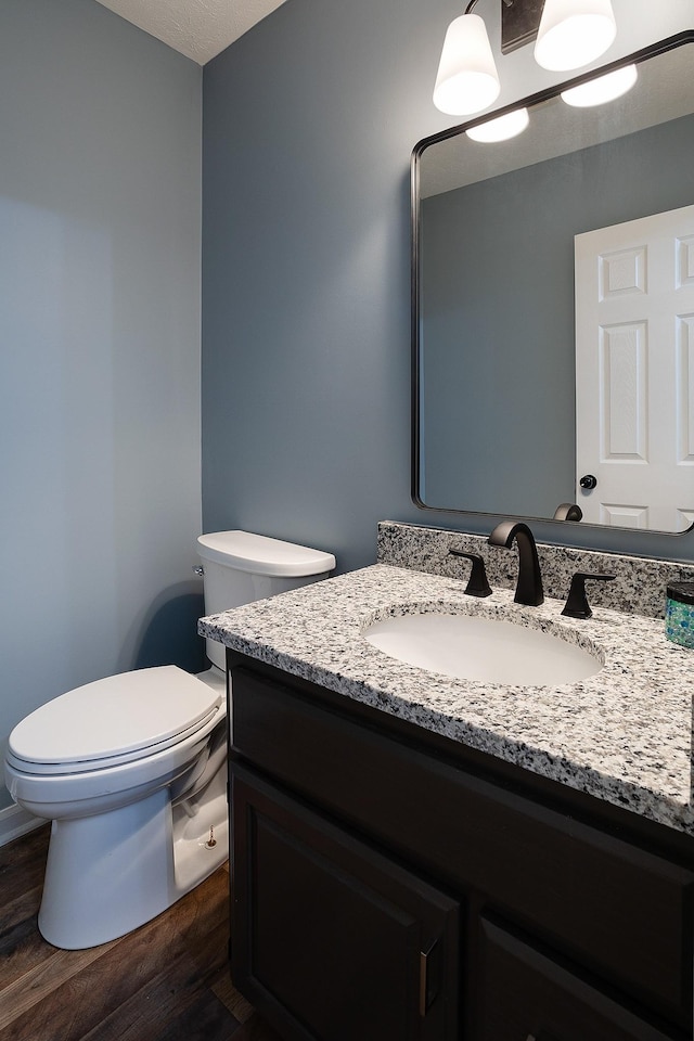 bathroom with toilet, wood finished floors, and vanity