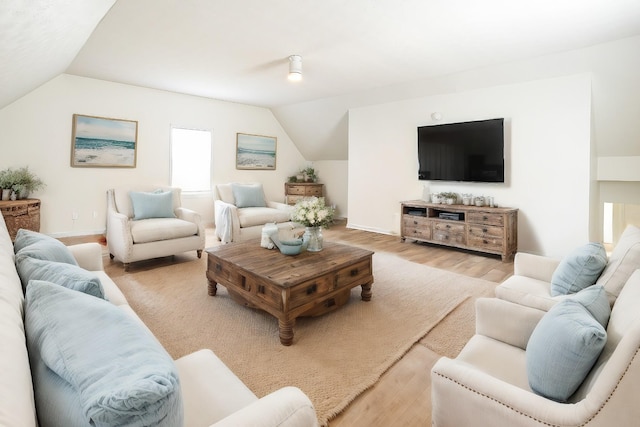 living room with light wood-style floors, vaulted ceiling, and baseboards