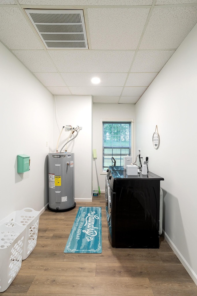 interior space featuring electric water heater, visible vents, baseboards, and wood finished floors